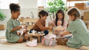 Children arranging dolls and pretend play props together in a bright playroom